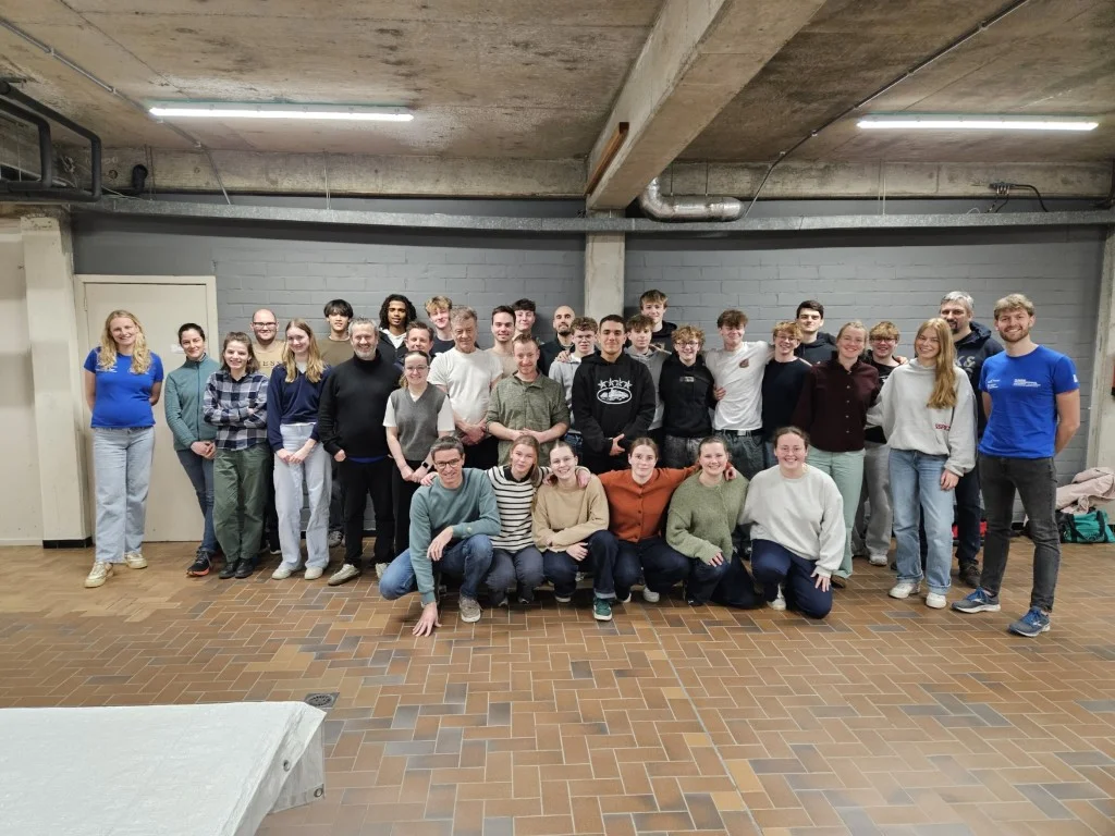 Groepsfoto van een cursusgroep Hoger Redder, staand en gehurkt in een zaal