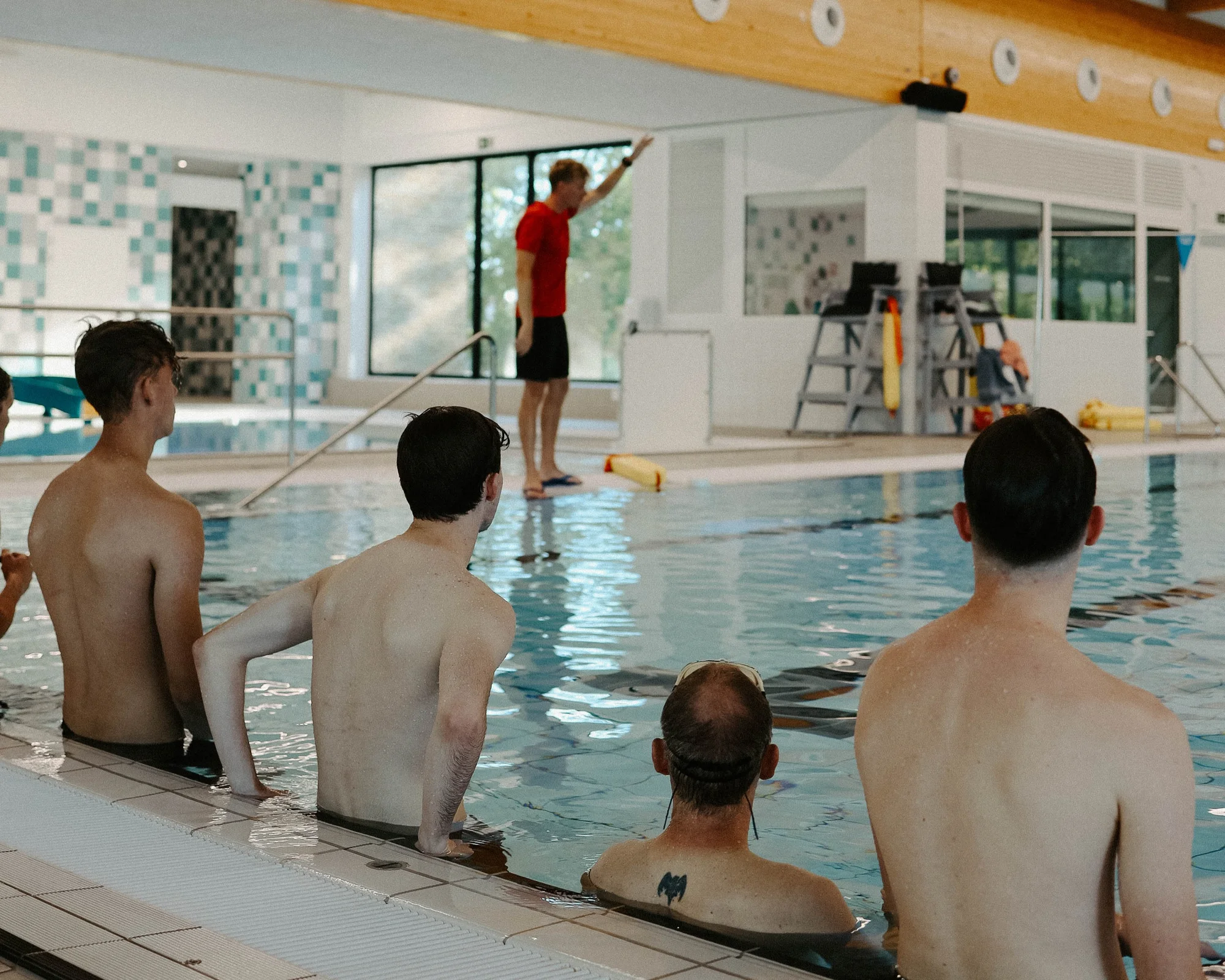 Cursisten in het water luisteren naar een lesgever op de badrand