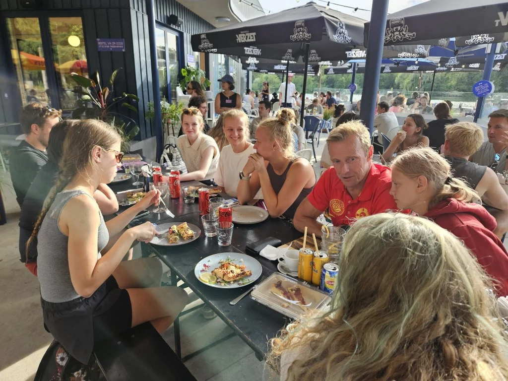 Een groep redders in zwemkledij op een rij op het strandje aan het meer